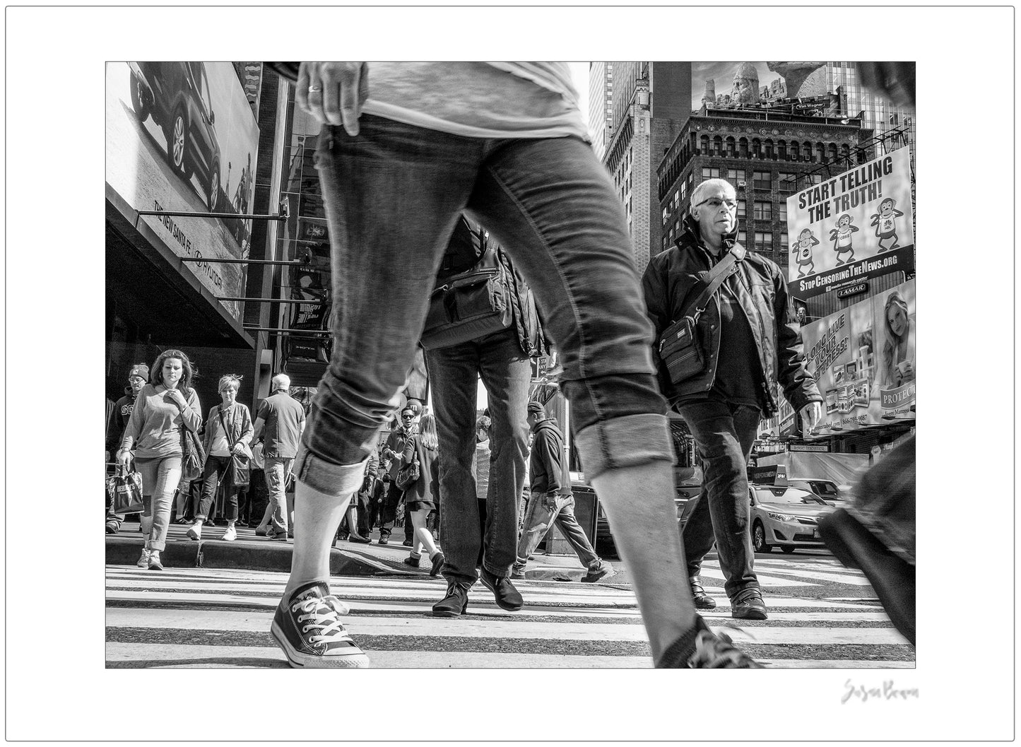 Black & White photograph of people walking in Times Square with low perspective