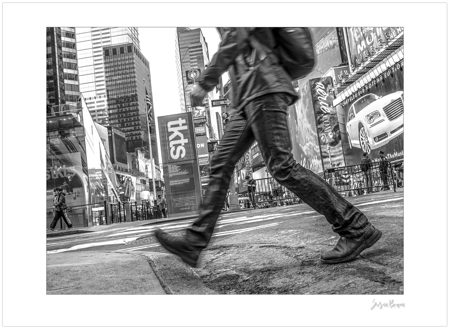 Black & White photograph of people walking in Times Square with low perspective