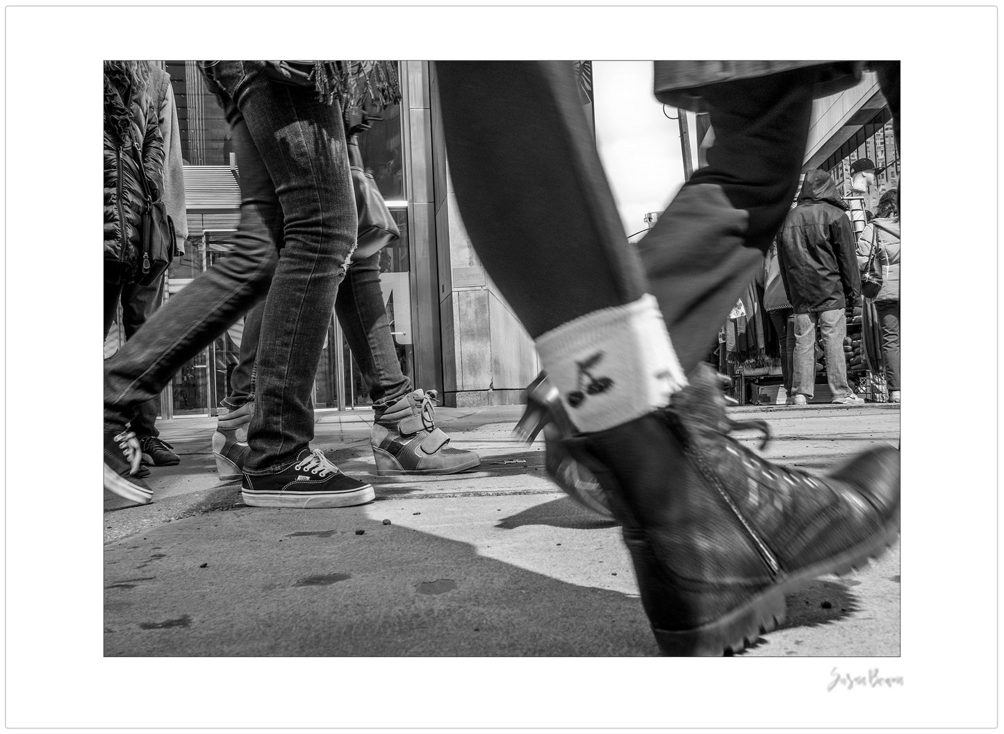 Black & White photograph of people walking in Times Square with low perspective
