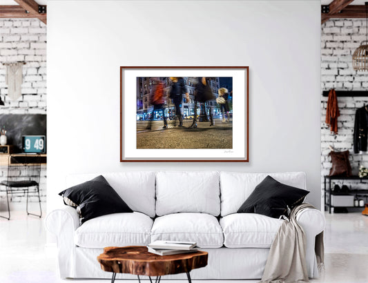 Photograph of 4 blurry people walking at night in New York City with low perspective