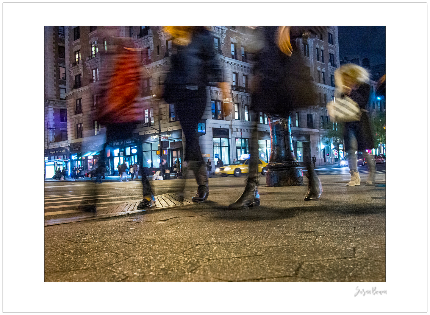 Photograph of 4 blurry people walking at night in New York City with low perspective
