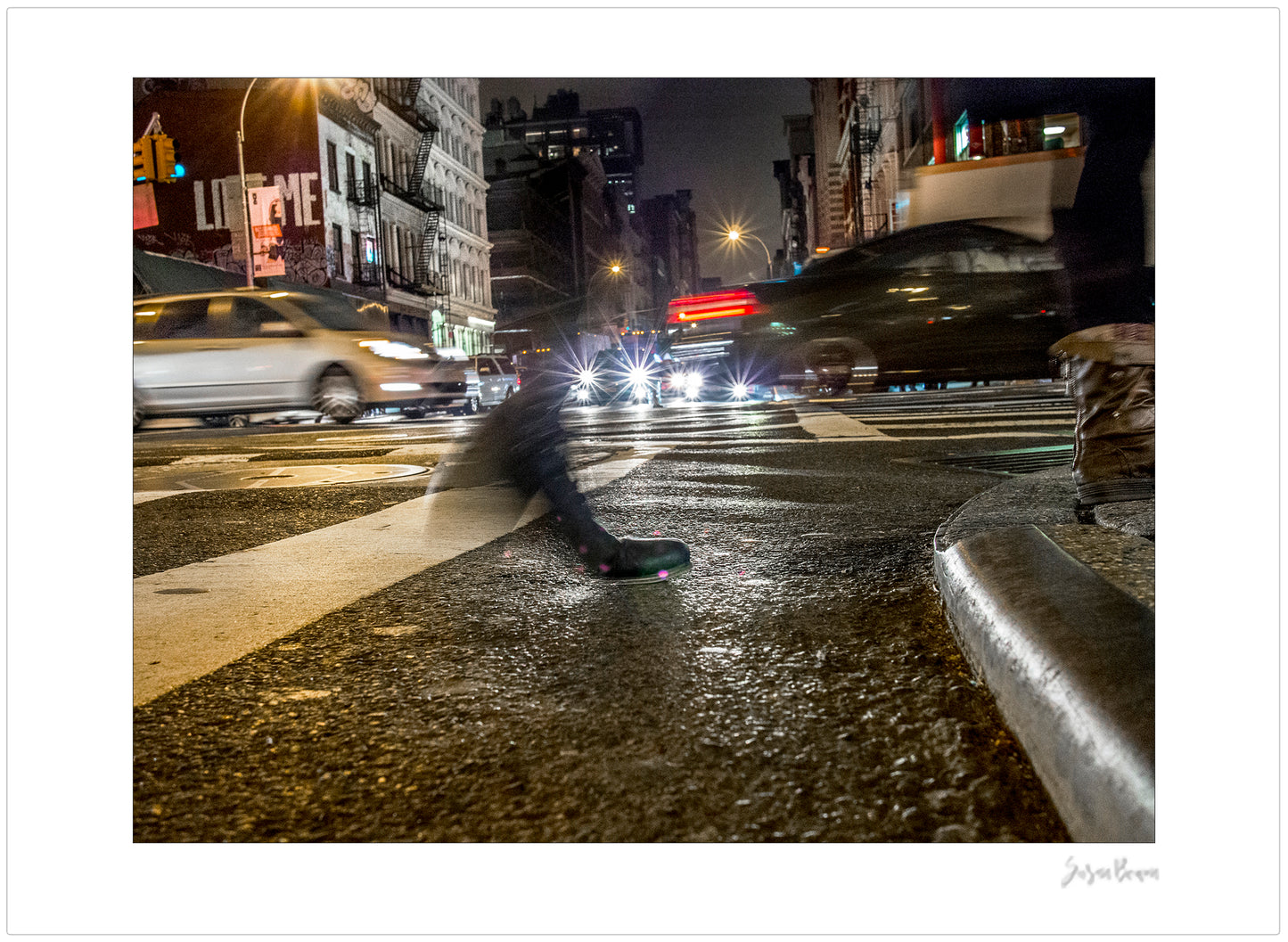 Photograph of a blurred foot crossing wet pavement in Chinatown at night in New York City with low perspective