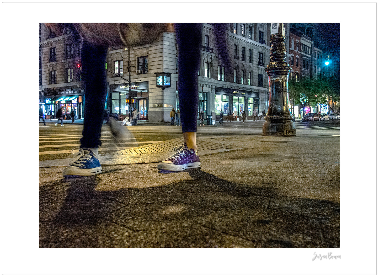Photograph of two mis-matched legs of different people at night in New York City with low perspective