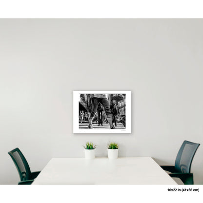 Times Square View Between Legs artwork by Susan Bowen, shown as 16x22 print. Features low-angle B&W street photograph of pedestrians mid-stride in Times Square, legs looming large against the city.
