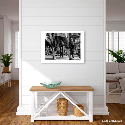 Times Square View Between Legs artwork by Susan Bowen, shown as 24X33 print. Features low-angle B&W street photograph of pedestrians mid-stride in Times Square, legs looming large against the city.
