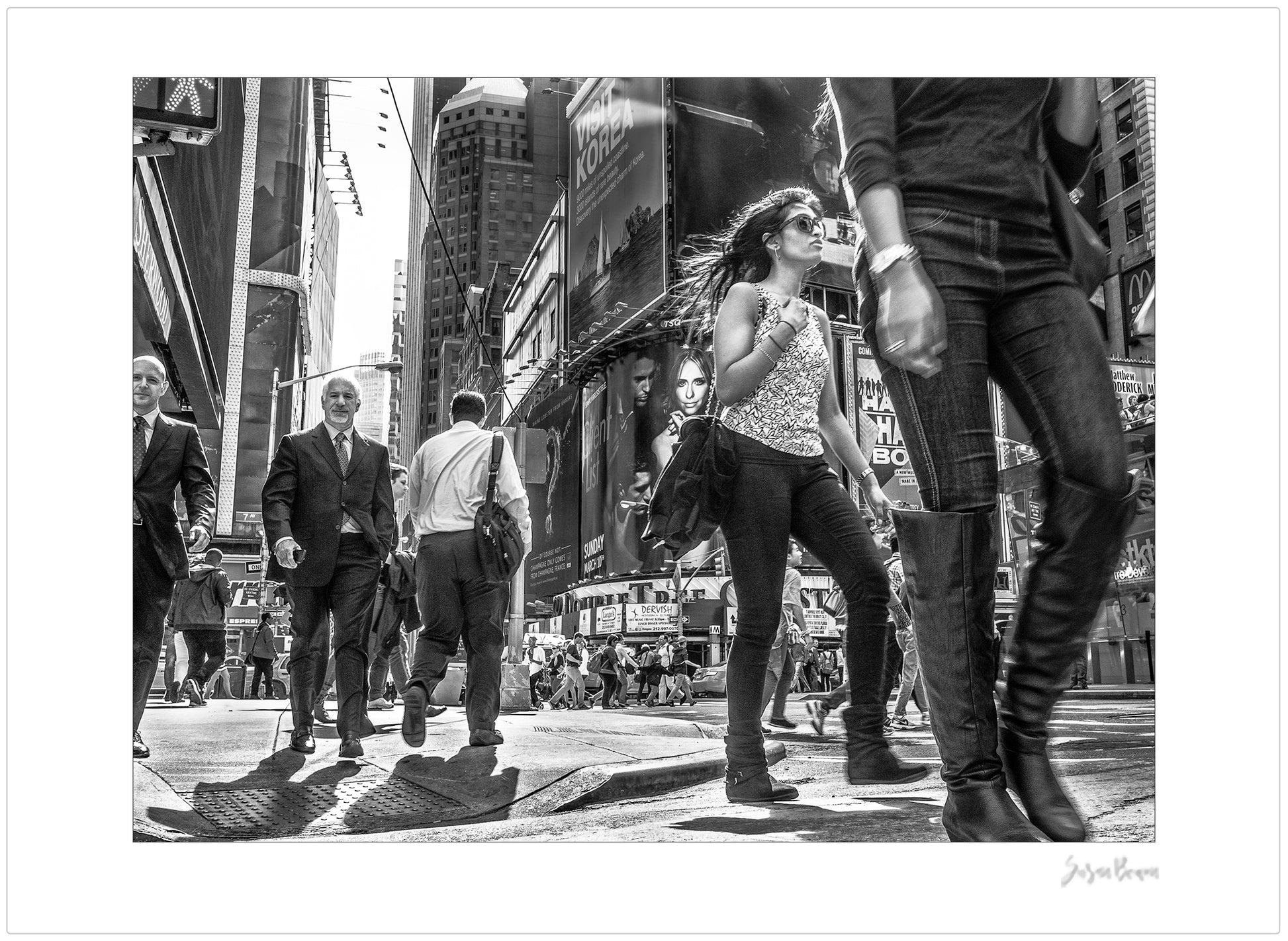 Black & White photograph of people walking in Times Square with low perspective