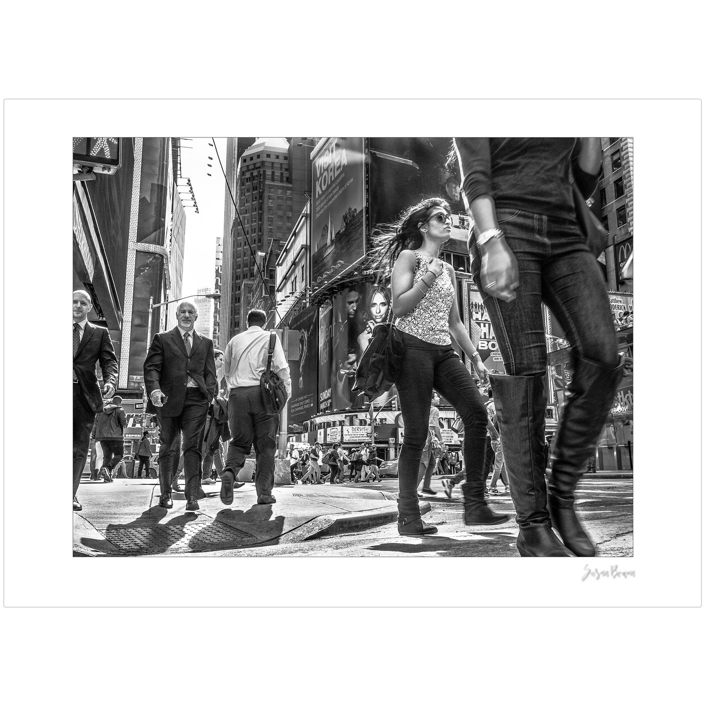 Black & White photograph of people walking in Times Square with low perspective