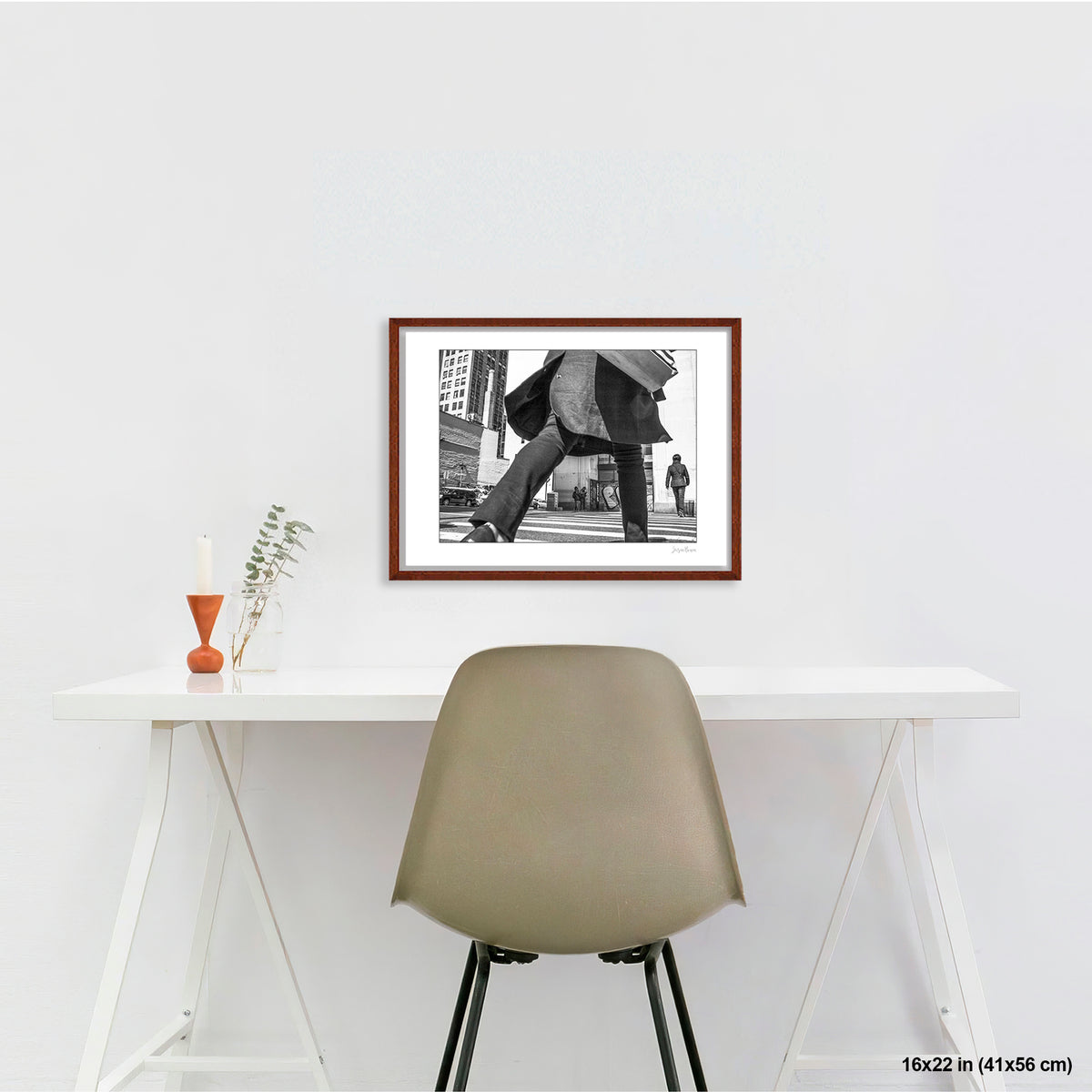 Canal Street Looming Figure artwork by Susan Bowen, shown as 16x22 framed print. Features low-angle B&W photograph of a figure mid-stride at Canal Street, coat billowing, dwarfing the city behind them.