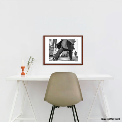 Canal Street Looming Figure artwork by Susan Bowen, shown as 16x22 framed print. Features low-angle B&W photograph of a figure mid-stride at Canal Street, coat billowing, dwarfing the city behind them.