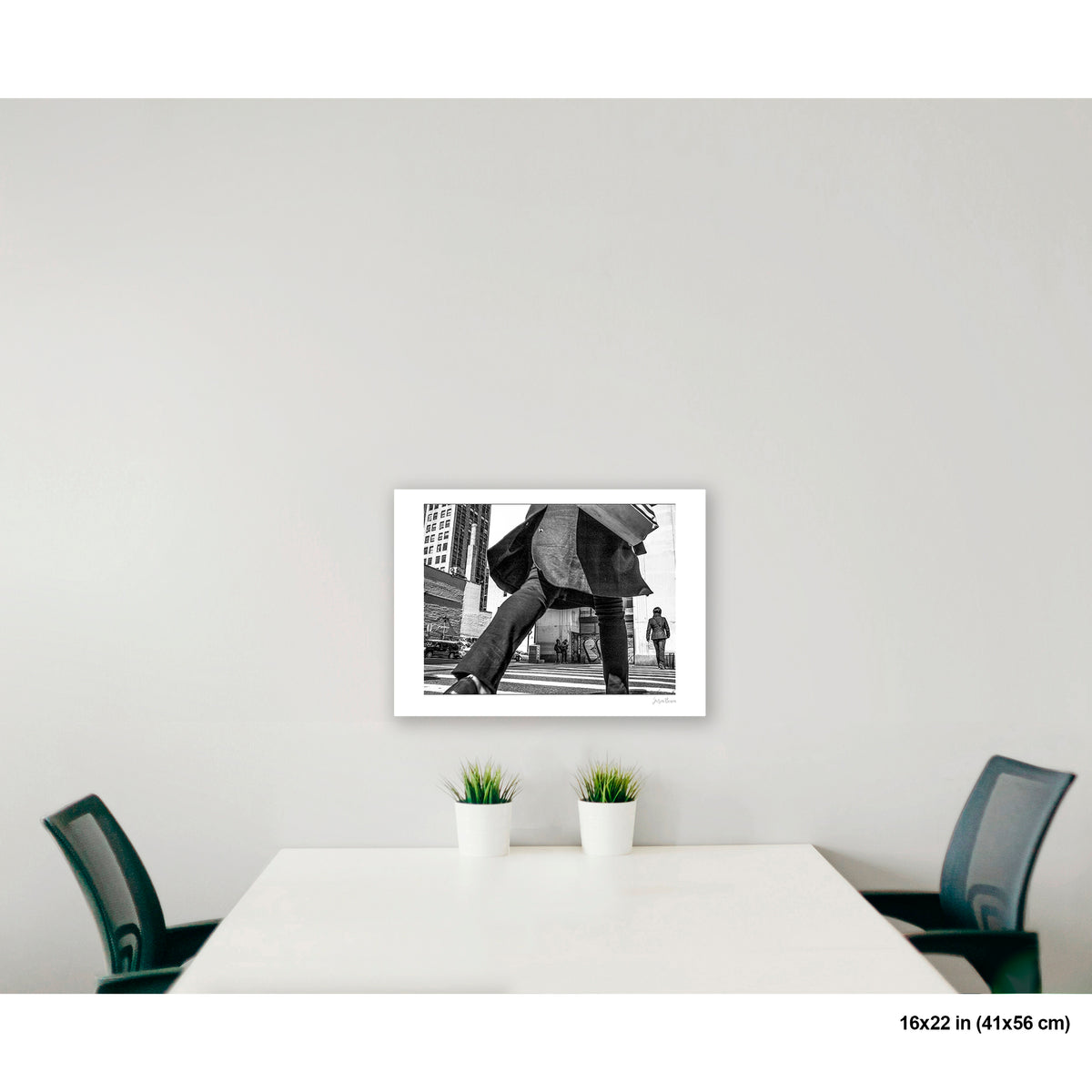Canal Street Looming Figure artwork by Susan Bowen, shown as 16x22 print. Features low-angle B&W photograph of a figure mid-stride at Canal Street, coat billowing, dwarfing the city behind them.