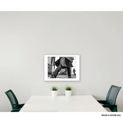 Canal Street Looming Figure artwork by Susan Bowen, shown as 16x22 print. Features low-angle B&W photograph of a figure mid-stride at Canal Street, coat billowing, dwarfing the city behind them.