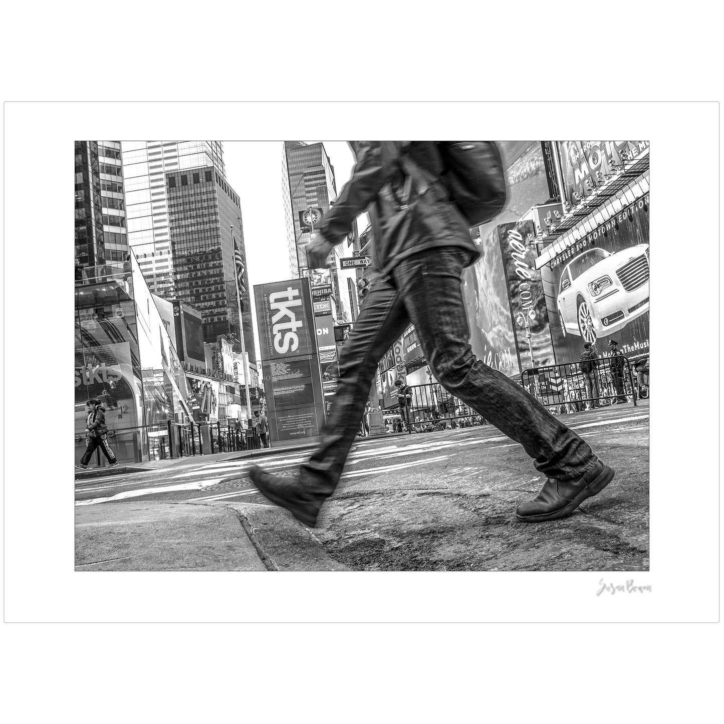 Black & White photograph of people walking in Times Square with low perspective