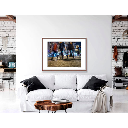 Photograph of 4 blurry people walking at night in New York City with low perspective
