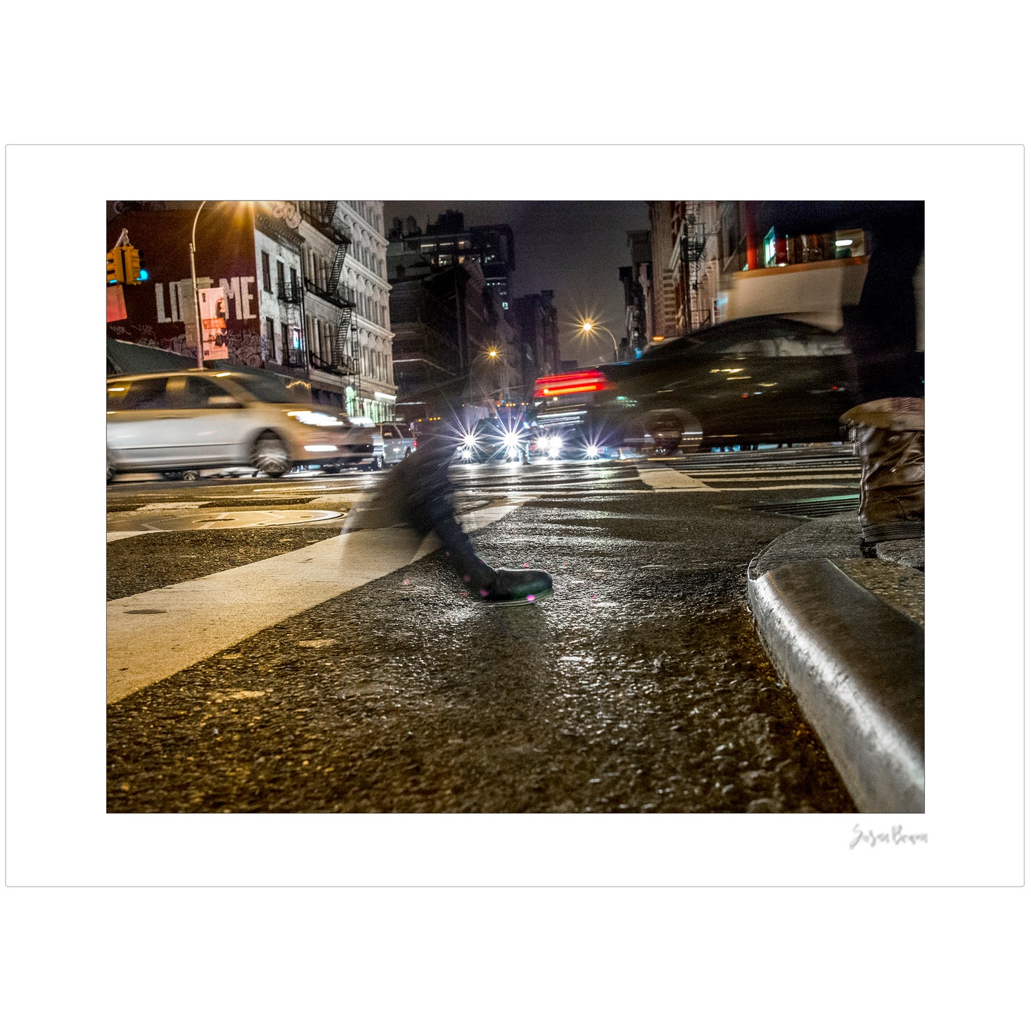 Photograph of a blurred foot crossing wet pavement in Chinatown at night in New York City with low perspective